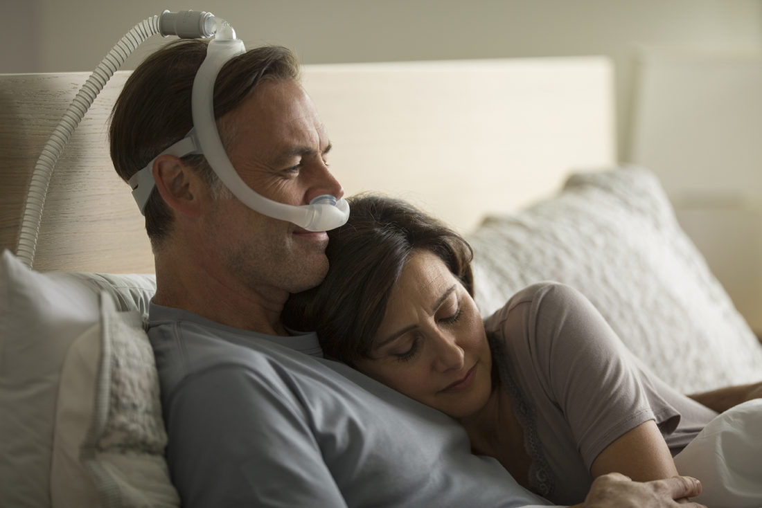 man using a cpap machine being held by his wife